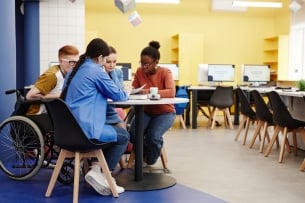 Vibrant full-length shot of diverse group of students studying together at table in college lab