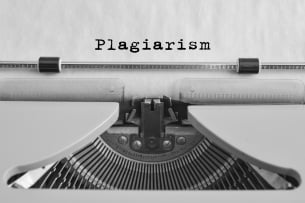 A black-and-white image of a typewriter fed with a piece of paper with a single typed word: "Plagiarism."