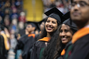 A graduate student at Wright State smiles during a commencement ceremony.
