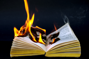 An open book, on fire, against a black background.