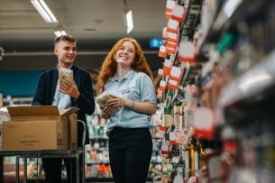 Two young employees working together in grocery store.