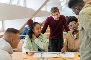 A group of multiracial students talk in the library.