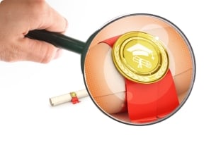Magnifying glass is held up over a diploma