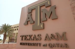 A brown building facade that reads Texas A&M University at Qatar