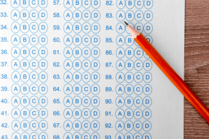 A pencil lies atop a score sheet with multiple choice bubbles for a standardized test.