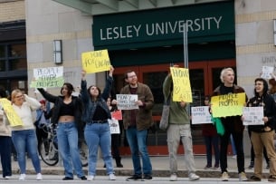 A photo of protestors holding signs objecting to job cuts at Lesley University.