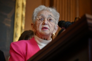 Virginia Foxx stands at a podium in a pink blazer