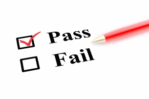 "Pass" is checked on a white paper with two options, "Pass" and "Fail." A red pen lies to the side.