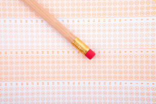 A number 2 pencil lies on a blank standardized test answer sheet filled with multiple choice bubbles.