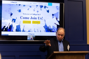 Man at dais in front of video screen