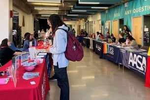 A student speaks with ASU staff members at a resource fair on campus