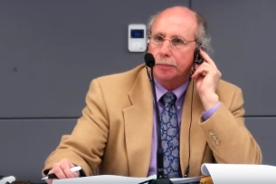 Andy Everman, the chair of Mott Community College, sits in front of a microphone. 