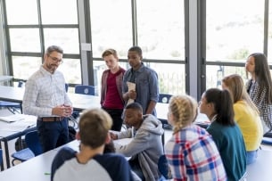 Multiethnic students and male teacher are discussing at school. They are casually dressed.