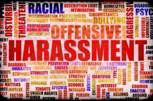 A word cloud featuring words associated with harassment. The word “harassment” is largest and in the center. Other prominently featured words (among dozens) include “offensive,” “racial,” “bullying,” “aggressive,” and “threatening.”