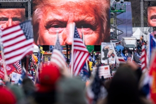 Large images of former president Trump's face on video screens loomed over a crowd of his supporters, many bearing American flags, as they gathered at the White House on Jan. 6, 2021.