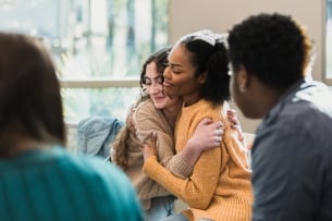 Two students hug each other in a support circle