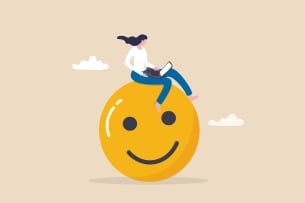 An illustration of a woman with an open laptop sitting atop a large yellow smiley face.