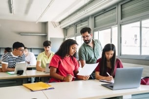 Friendly professor explaining exercise to students in a classroom