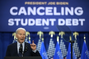 President Biden in front of a blue sign with white letters that says "Canceling Student Debt"