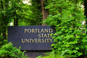 A photo of a Portland State University sign flanked by trees.