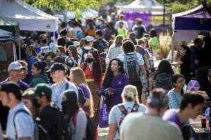 A crowd mills on a campus between vendor tents
