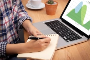 A student takes notes while engaging with a lecture online.