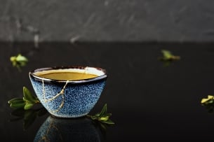 A blue ceramic bowl with its cracks mended with gold in the kintsugi style
