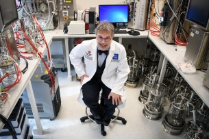 A photograph of Dr. Peter Hotez in a white lab coat, surrounded by technology.