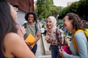 Multiethnic group of college students looking very happy talking at school and laughing
