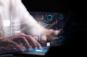 A programmer works on a laptop looking at charts and code