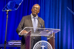 Tennessee State University interim president Ronald Johnson stands in front of a university podium.