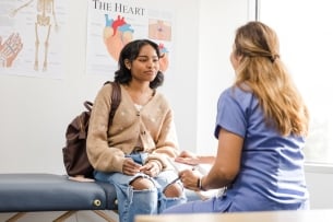 A college student listens intently to a female health-care practicioner in a doctor's office