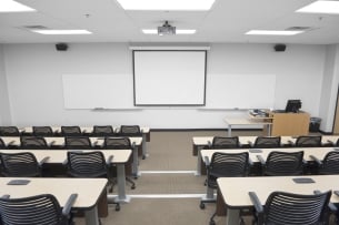 An empty college classroom, with a blank whiteboard at the front.