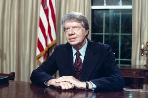 Former president Jimmy Carter, who died Dec. 29, is seated at his desk in the Oval Office on April 18, 1977.