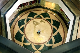 A worker crosses the world map embedded in the floor of the rotunda area inside Founders Hall on the campus of Soka University of America.
