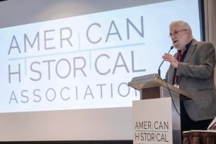 A photograph of Jim Grossman speaking into the mike at a lectern in front of a screen. Both the lectern and screen say "American Historical Association."