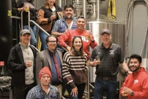 Staff from Western Oregon University and Xicha Brewing pose for a photo holding draft beers