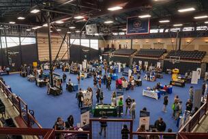 Students and employers interact during Lebanon Valley College's first Success Expo. The event is in a gymnasium with many booths on a blue carpet floor.