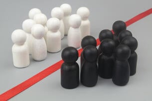 Groups of white and black people-like figurines are divided from one another by color, with a red line separating the two groups.