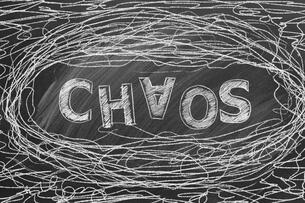 A black-and-white illustration of the word "Chaos," with the A upside down, surrounded by a messy doodle amounting to tangled lines.