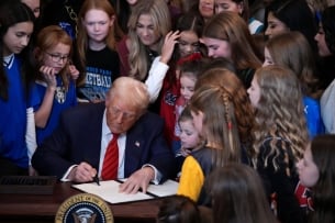 Trump signs EO surrounded by a crowd of young girls