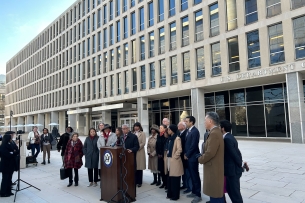 Lawmakers stand at a podium outside the Education Department building
