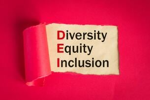 The words diversity, equity and inclusion can be seen against the backdrop of a torn magenta-colored page.