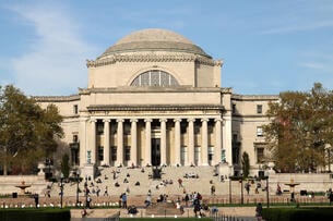 An image of the classical-style Low Memorial Library at Columbia University. Students can be seen sitting on its steps.