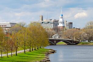 A photo of the Harvard University campus from across the Charles River in springtime, with leaves on trees just beginning to bud.