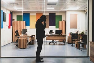Lone person in silhouette standing in front of glass-windowed office