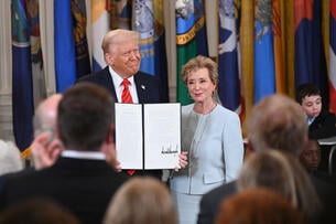A photo of President Trump and Secretary of Education Linda McMahon: Trump holds up his signed executive order directing the dismantlement of the Department of Education. Both are smiling.