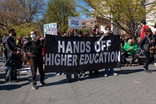 Protesters hold a bold sign that reads "hands off higher education."