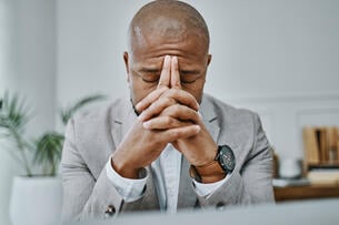 A man leans his head against his hands in an office.
