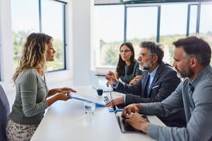 A female job candidate sits across from a group of three people in a job interview.